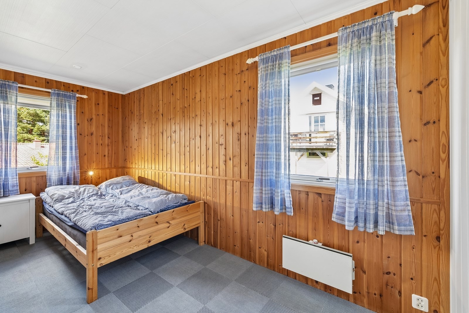Soverom med vegger i trepanel og teppefliser på gulvet. Galleribilde