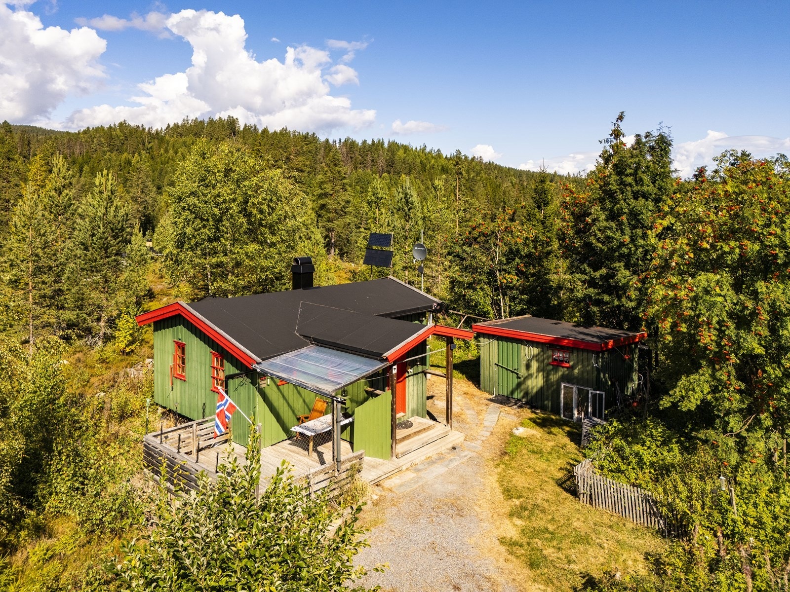 Fritidseiendom fra 1966 med hytte og separat uthus, beliggende i skogsterreng. Galleribilde