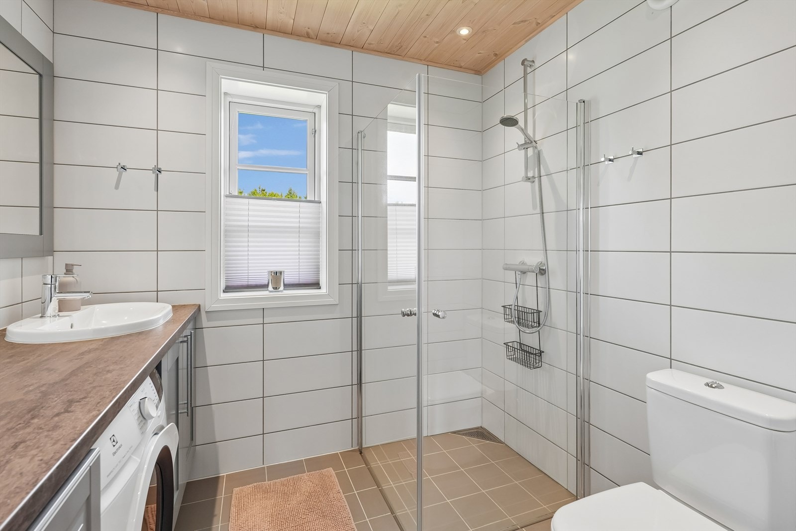Badet er lyst og delikat med flislagte vegger og gulv, samt varmekabler i gulvet. Her er det innredning med laminat benkeplate og nedfelt servant, innfellbare dusjvegger i hjørne, toalett og opplegg for vaskemaskin. Galleribilde