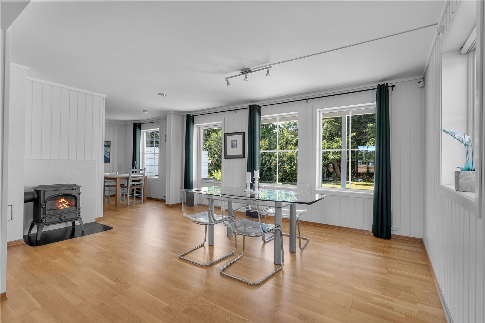 Store vindusflater slipper inn rikelig med dagslys og gir fri sikt til hagen, mens den koselige peisovnen skaper varme og atmosfære. Fra stuen er det direkte utgang til uteplassen. Galleribilde