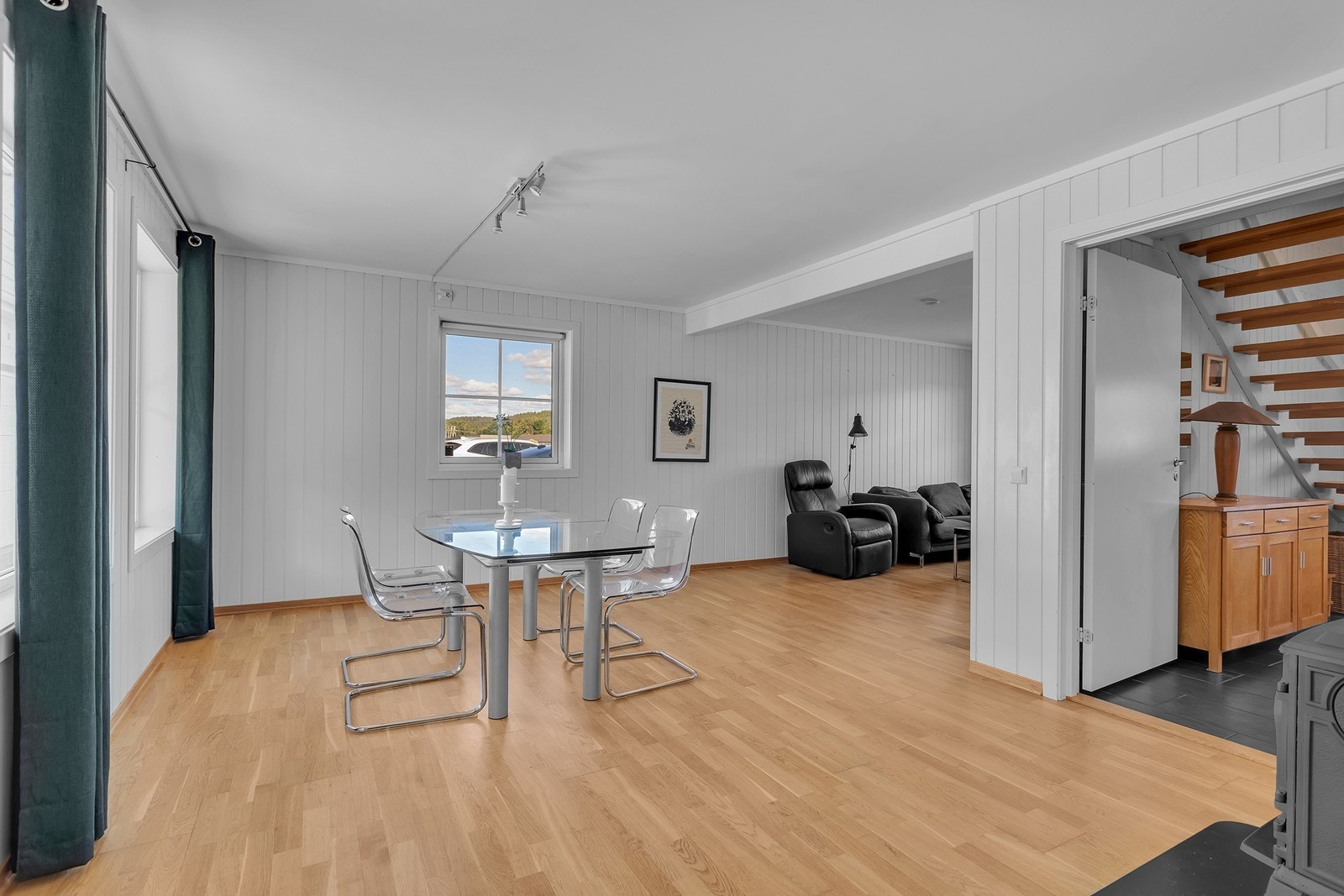Her møtes spiseplass og stue i en luftig, åpen løsning, med kort vei både til trappen opp og resten av boligens sosiale soner. Galleribilde