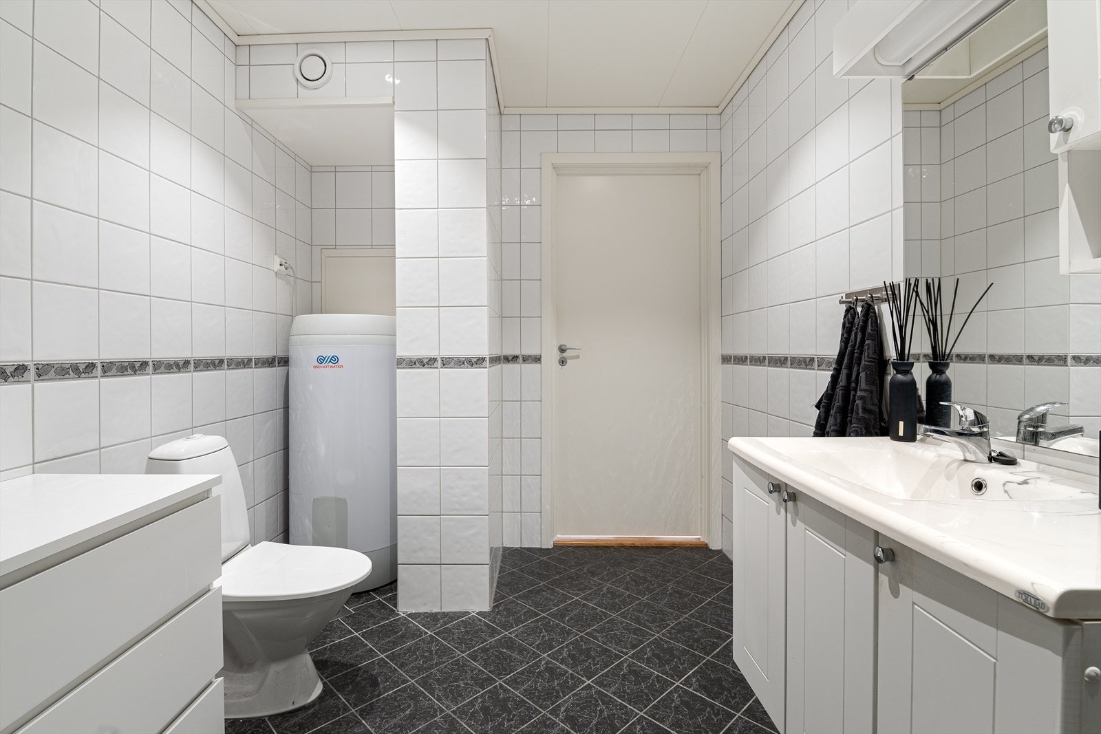Badet er praktisk innredet med nedfelt servant, toalett og dusjkabinett. Det er også opplegg for vaskemaskin Galleribilde
