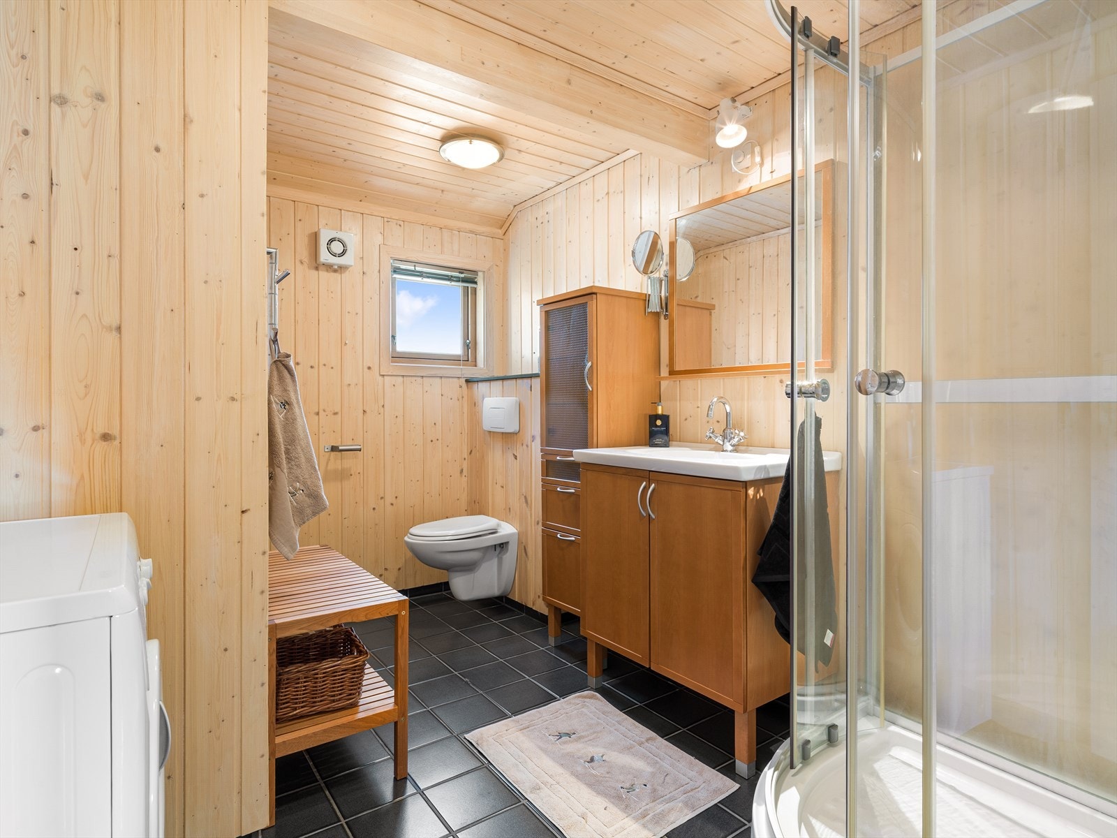 Badet er godt utstyrt med dusjkabinett, servantinnredning, vegghengt toalett og opplegg for vaskemaskin. Galleribilde