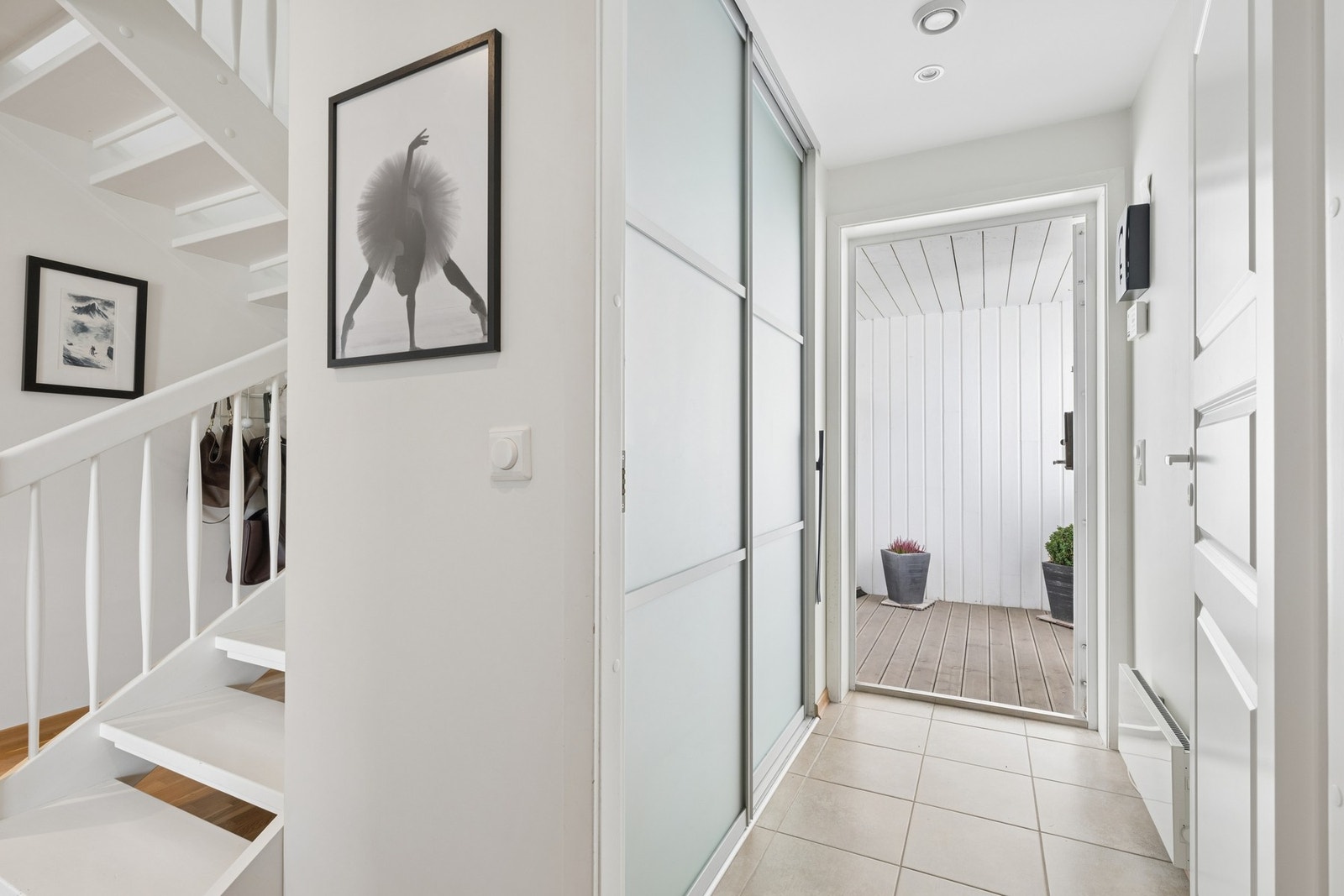 Lys entré med flislagt gulv og skyvedørsgarderobe for yttertøy. Galleribilde