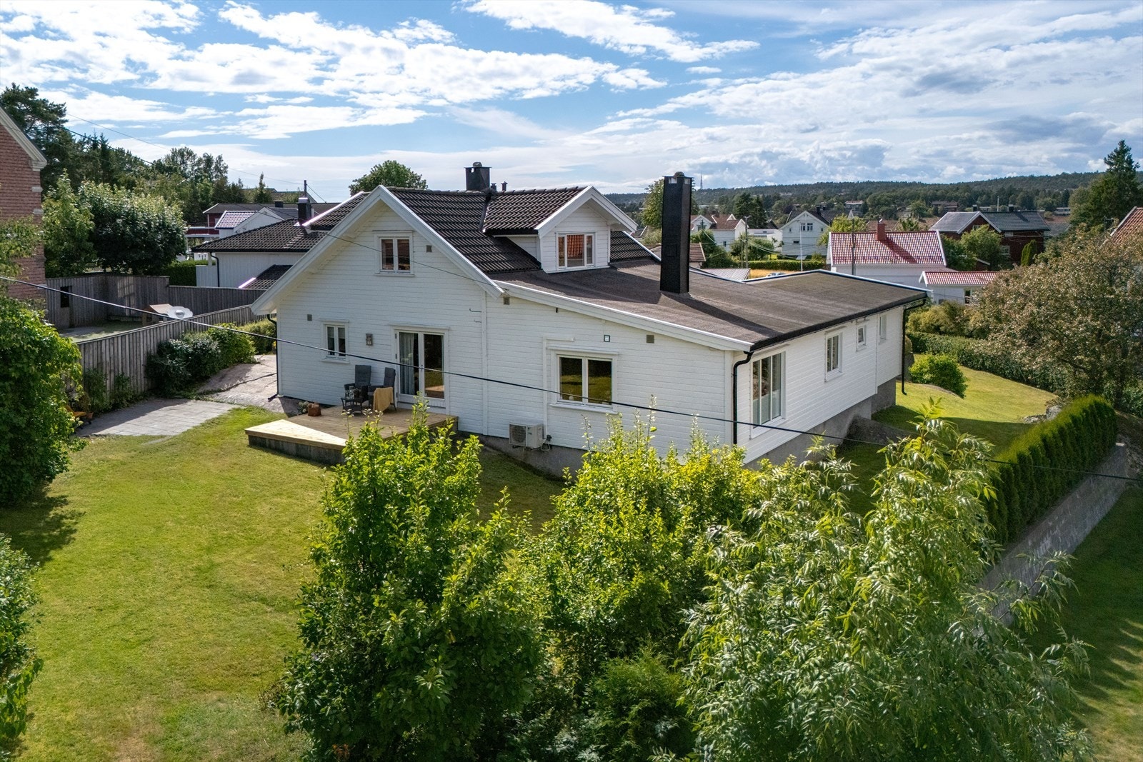 Den 1,3 mål store tomten er idyllisk og frodig med gressplen, støttemurer og en 70 kvm stor, vestvendt terrasse foran boligen. Hekker og levegger skaper en lun og skjermet atmosfære. Galleribilde