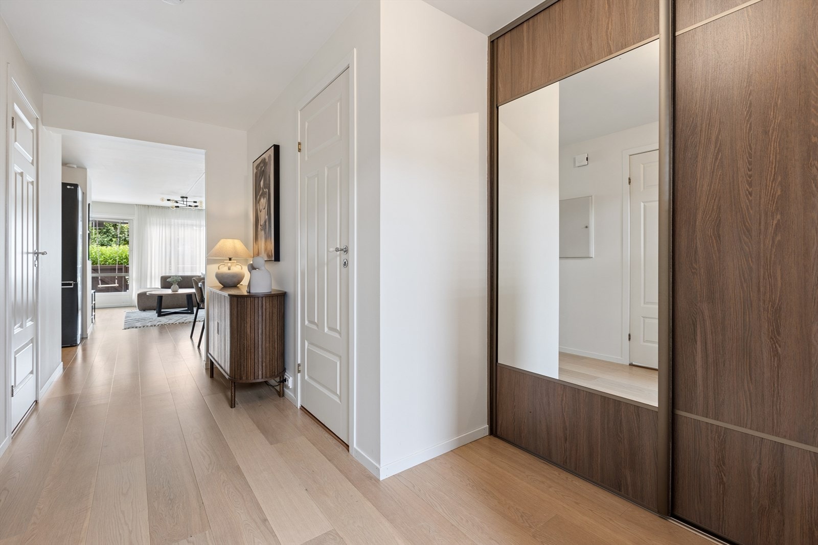Man ønskes velkommen inn i en lys og luftig gang som er praktisk innredet med stor skyvedørsgarderobe som gir god plass til yttertøy og sko. Her får man umiddelbart et godt førsteinntrykk av boligen. Galleribilde