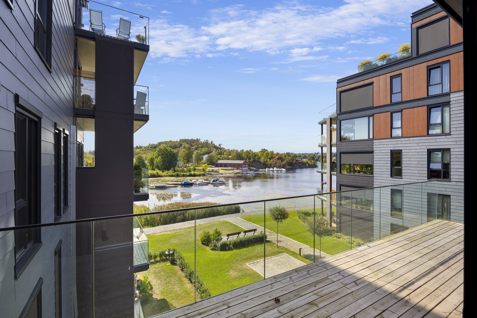 Balkongen er belagt med terrassebord og har rekkverk i glass for fri sikt. Galleribilde