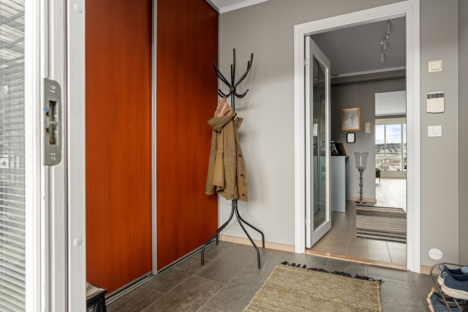Velkommen inn! Stor, flislagt gang med skyvedørsgarderobe.