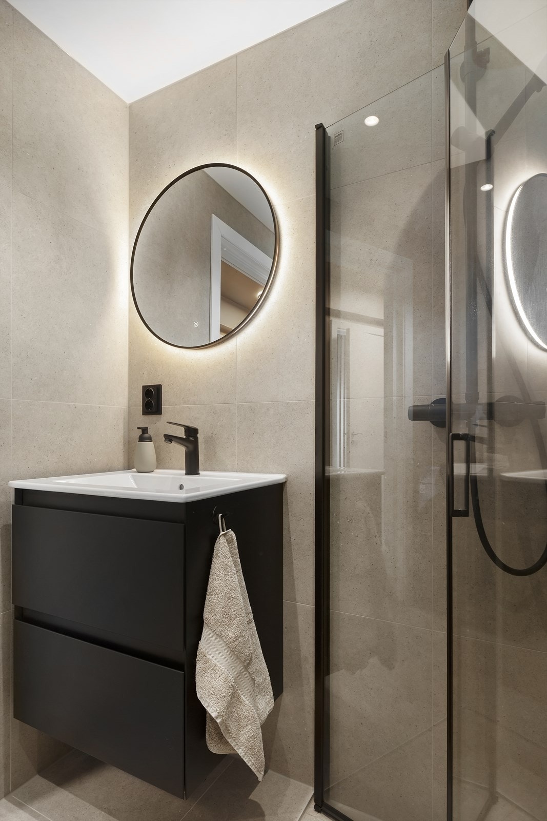 Badet har baderomsinnredning, speil med integrert belysning, dusjhjørne med regnfallsdusj og vegghengt toalett. Galleribilde