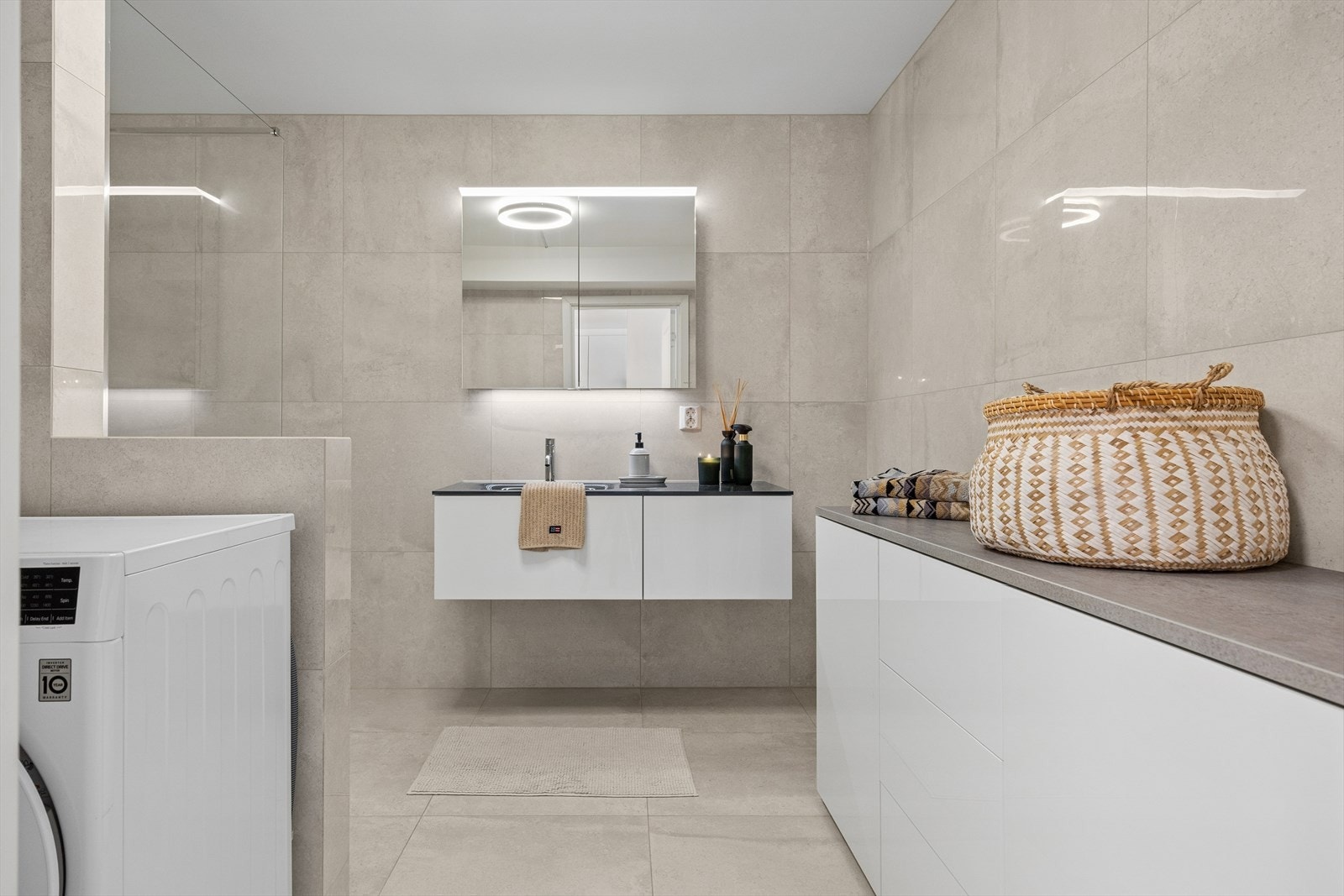 Badet ble oppgradert ca. 2021 og fremstår moderne med store fliser, varmekabler, innredning med LED-speil, romslig dusjsone med rainshower, toalett og opplegg for vaskemaskin. Galleribilde