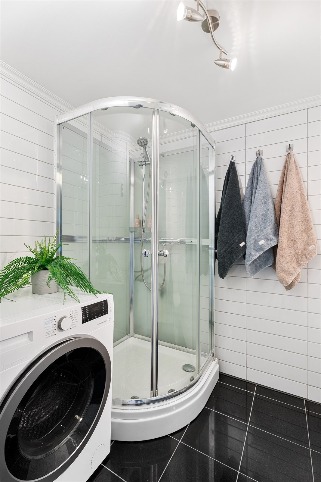 Praktisk dusjkabinett og god plass til vaskemaskin gjør badet både funksjonelt og lettstelt Galleribilde