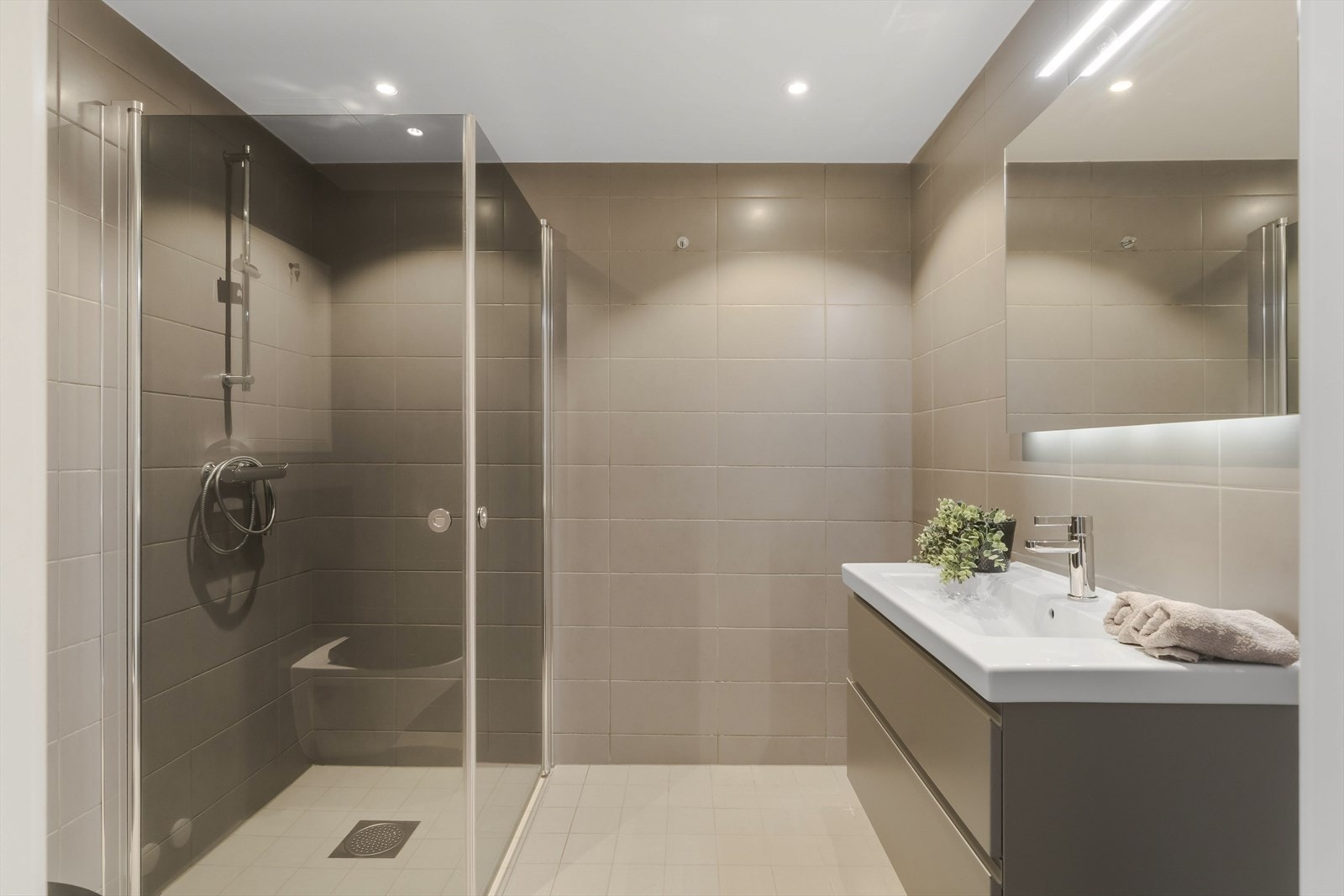 Badet fremstår som en elegant og innbydende del av boligen, med et moderne design og løsninger som kombinerer komfort og funksjonalitet. Galleribilde