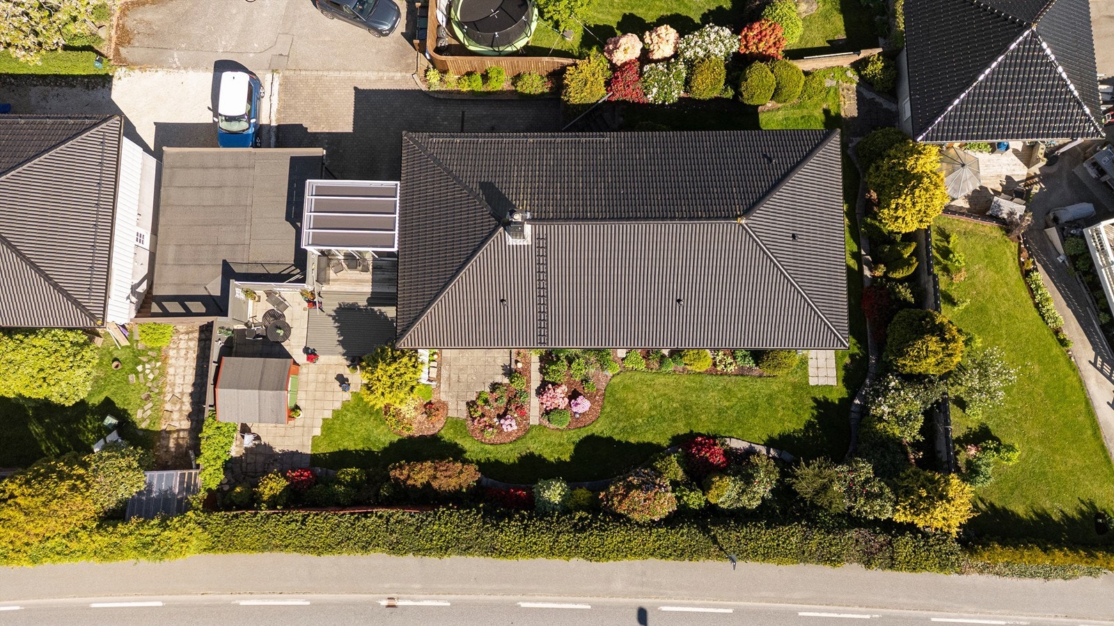 Tomten er opparbeidet med belegningsstein, plen og beplantning. Galleribilde