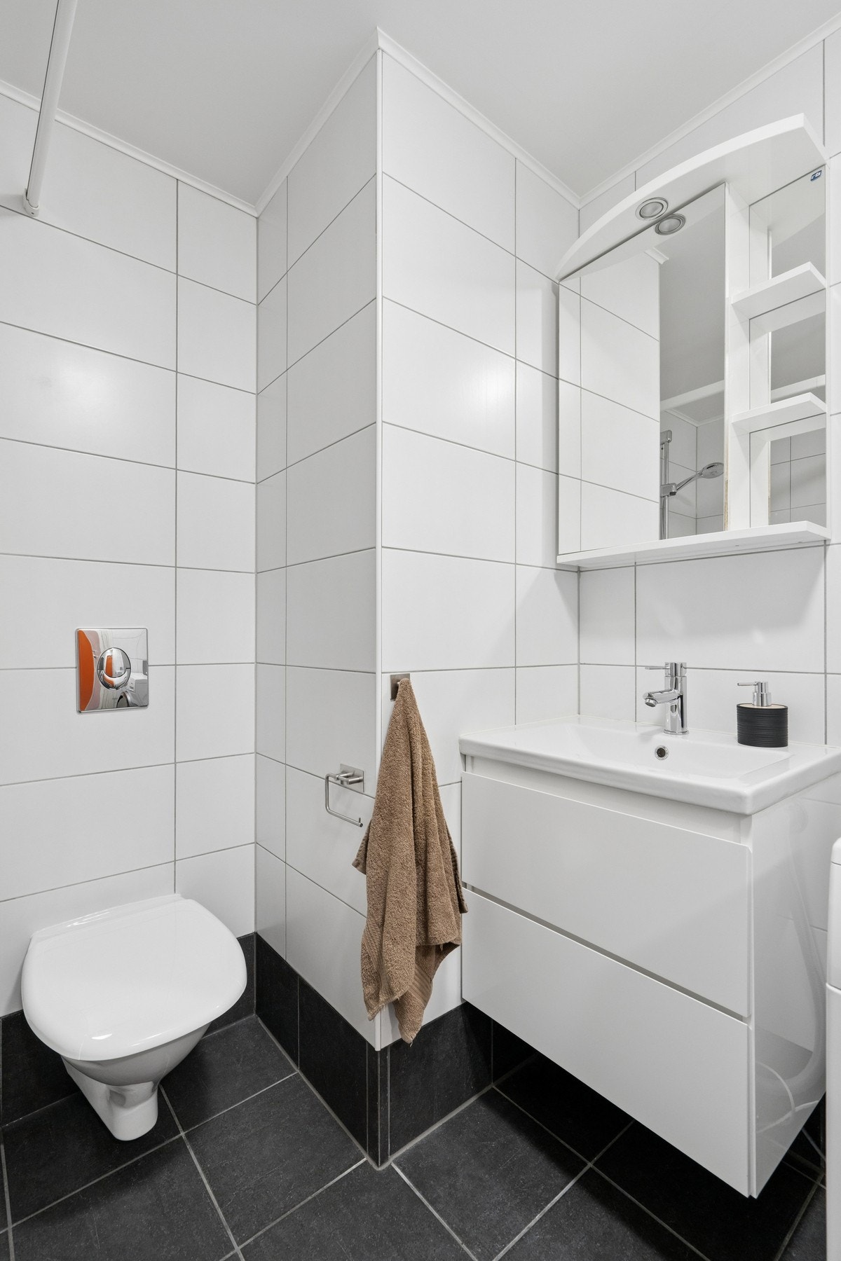 Badet er innredet med vegghengt toalett og servant med speilskap. Galleribilde