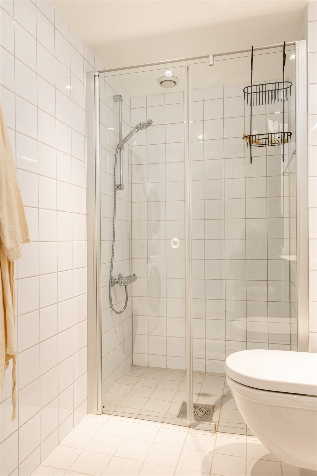 Videre er det dusjhjørne med glassvegger, vegghengt toalett og opplegg for vaskemaskin. Galleribilde