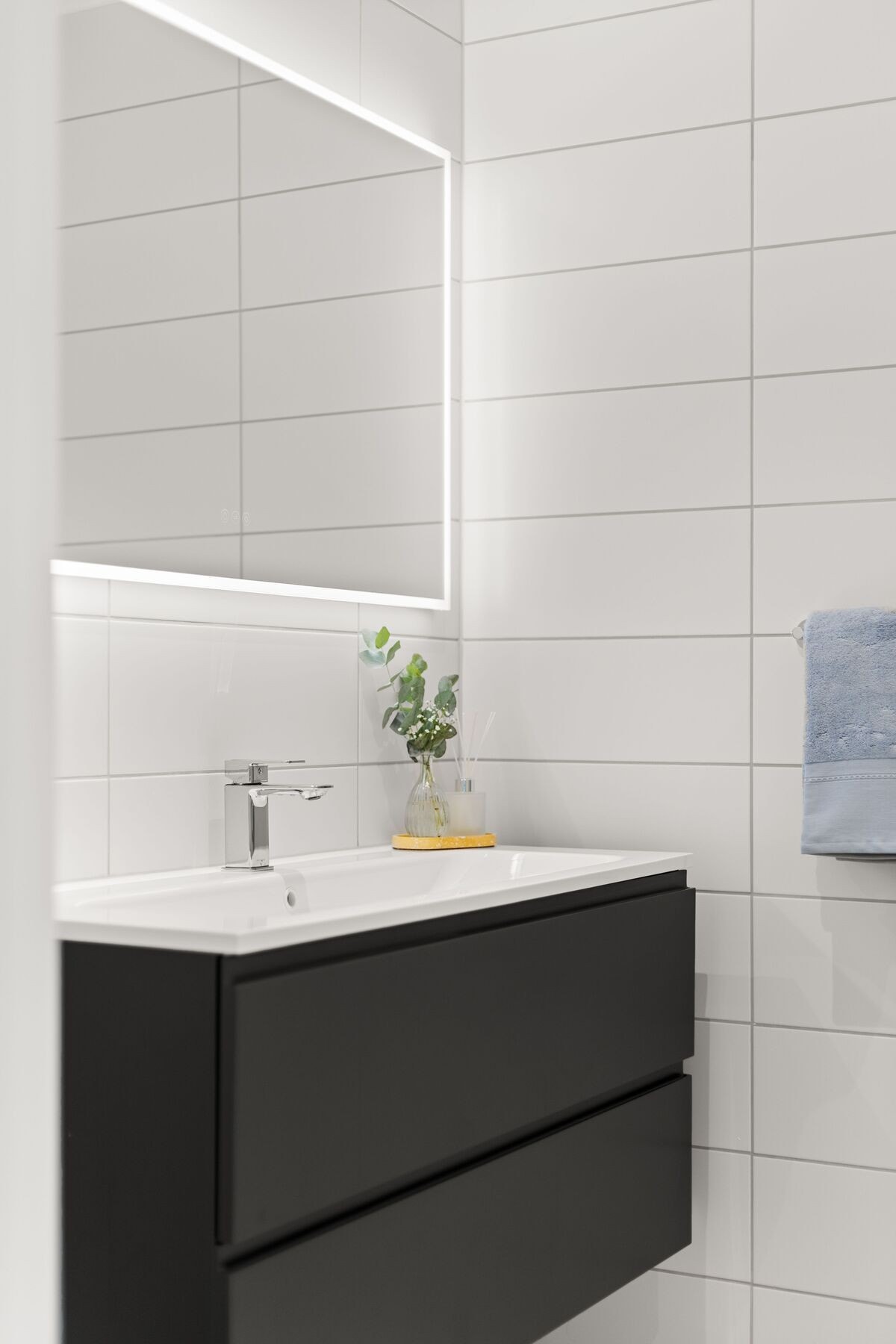 Badet på inngangsplanet har et rent og tidløst uttrykk med lyse fliser og mørk baderomsinnredning. Galleribilde