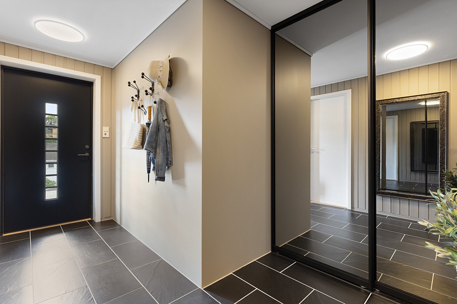 Innbydende gang med flislagt gulv og skyvedørsgarderobe med speil. Galleribilde