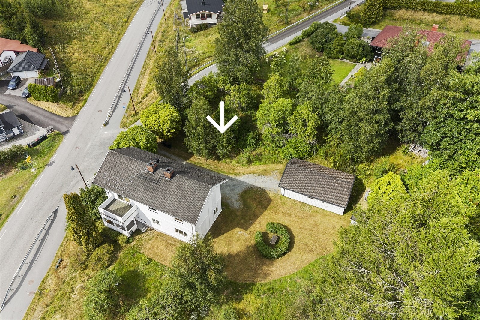 Eiendommen sett fra luften, som viser boligen, garasjen og tomten. Galleribilde