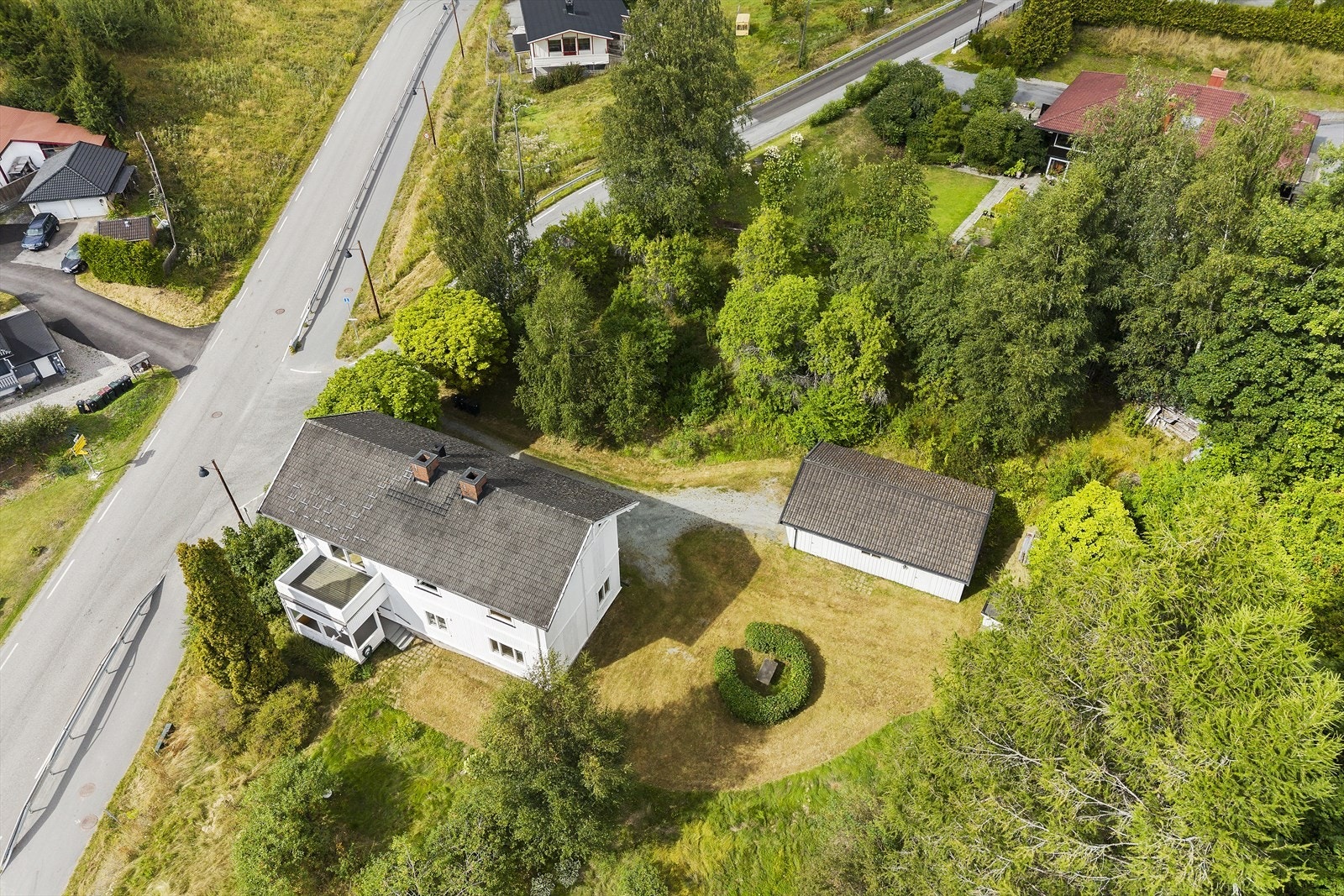 Eiendommen sett fra luften, som viser boligen, garasjen og tomten. Galleribilde