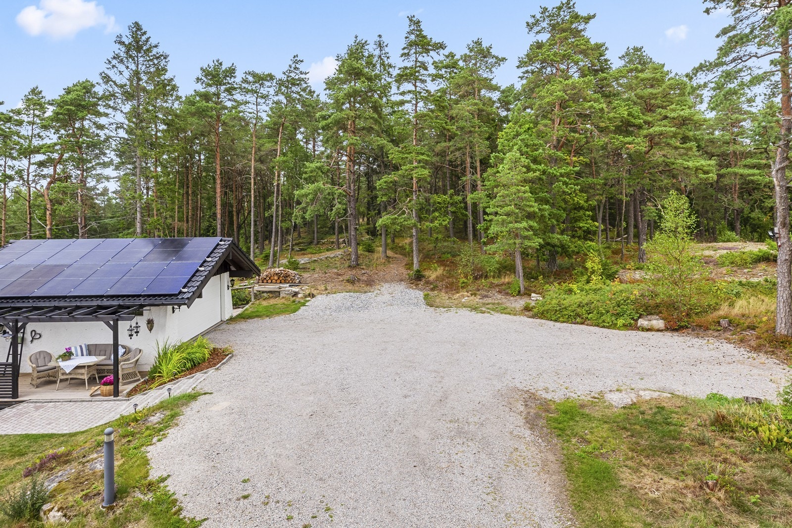 Stor, gruset gårdsplass med rikelig parkeringsplass. Galleribilde