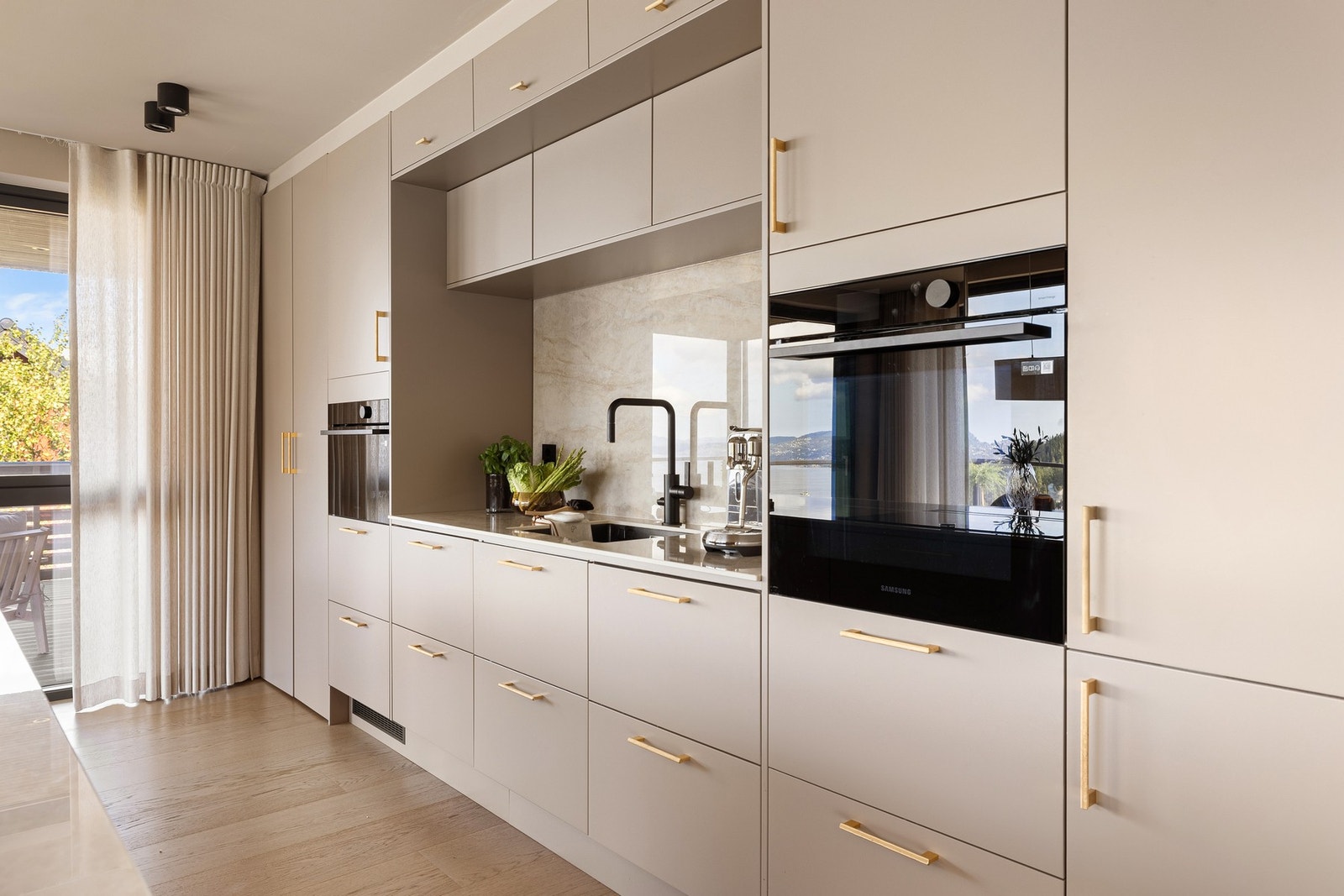 Kjøkkenet har slette fronter og benkeplate i stein - et elegant og tidløst materialvalg. Galleribilde