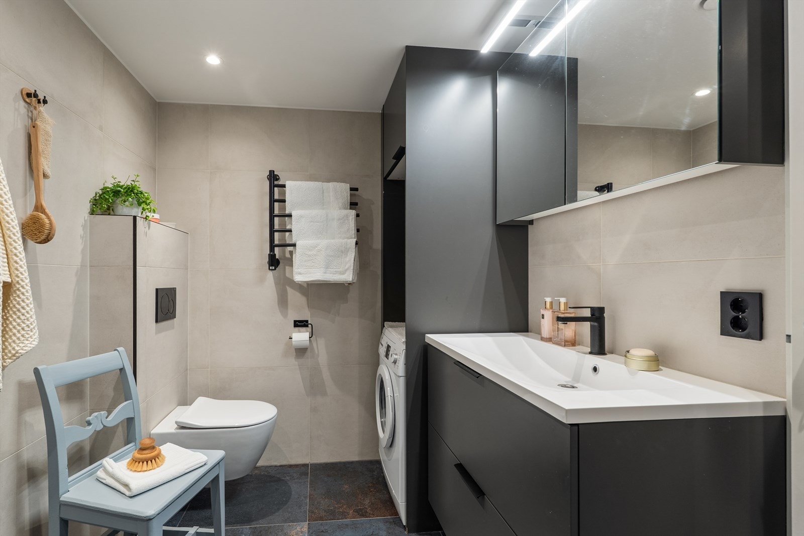 Badet er flislagt og har servant med skapinnredning, vegghengt toalett og opplegg for vaskemaskin. Galleribilde