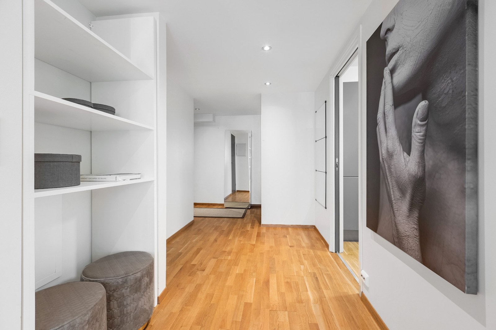 Lys og romslig gang som binder boligens ulike rom fint sammen, med praktisk åpen oppbevaringsløsning. Galleribilde