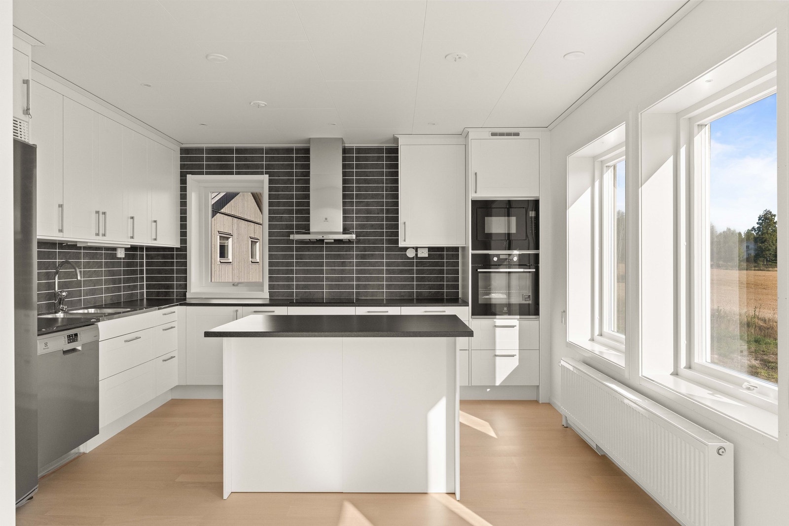 Kjøkken med hvite profilerte fronter, laminert benkeplate og hvitevarer fra Electrolux. Galleribilde