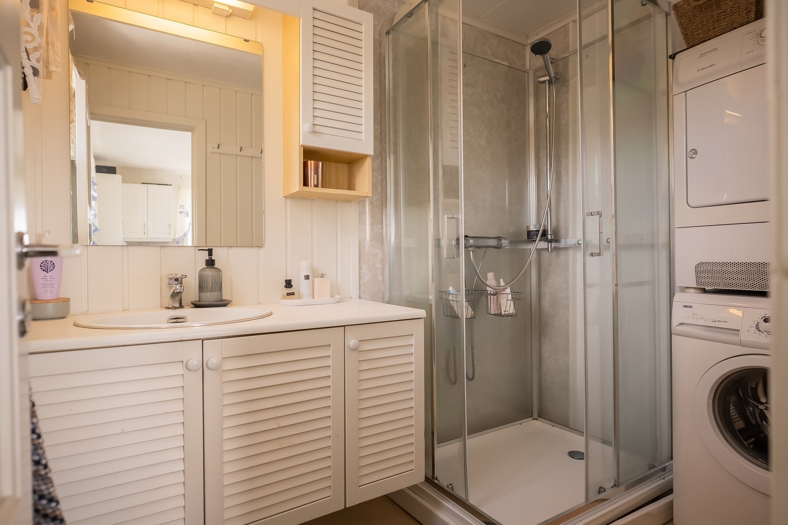 Badet er utstyrt med dusjkabinett, innredning med servant og opplegg for vaskemaskin. Galleribilde