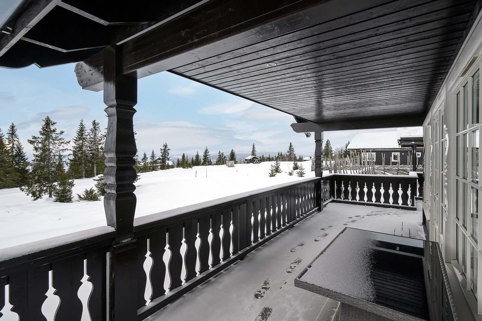 Eiendommen sett vinterstid. Verandaen er en god plass for å nyte omgivelsene. Galleribilde