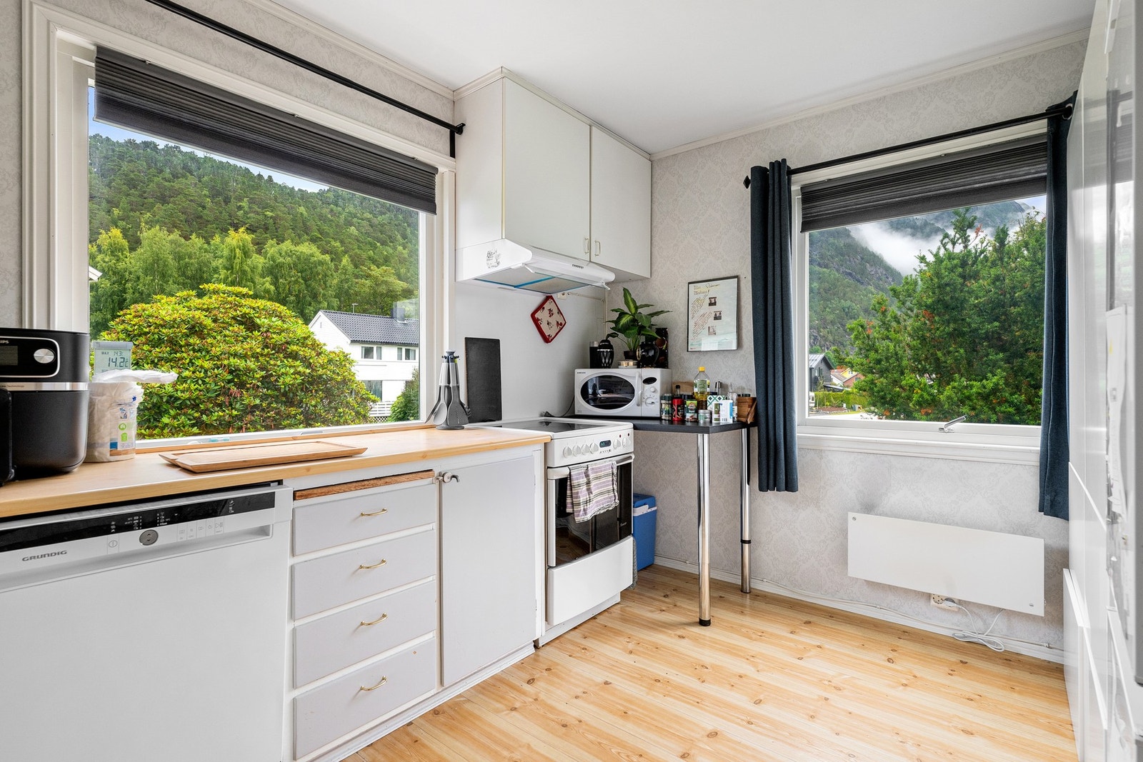 Kjøkken i 1. etasje. Eldre kjøkkeninnredning med malte profilerte fronter, laminat benkeplater og heldekkende oppvaskbenk i rustfritt stål. Galleribilde