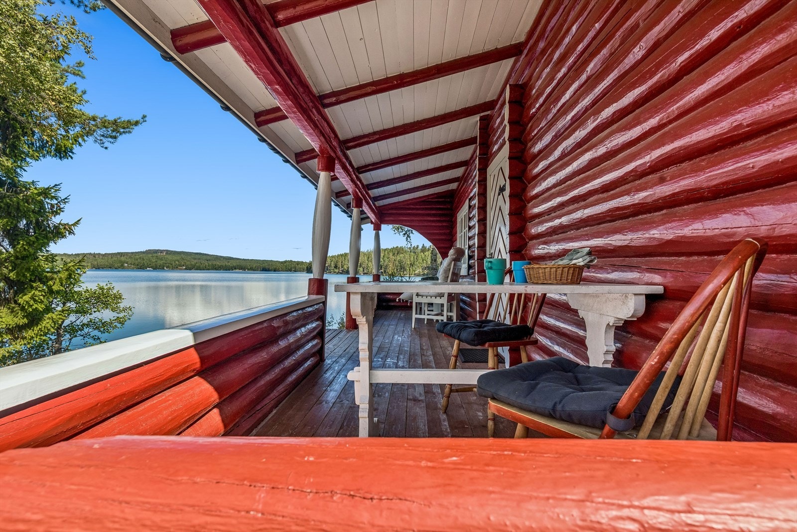 Overbygd treveranda ved inngangspartiet med utsikt over eiendommen og vannet. Galleribilde