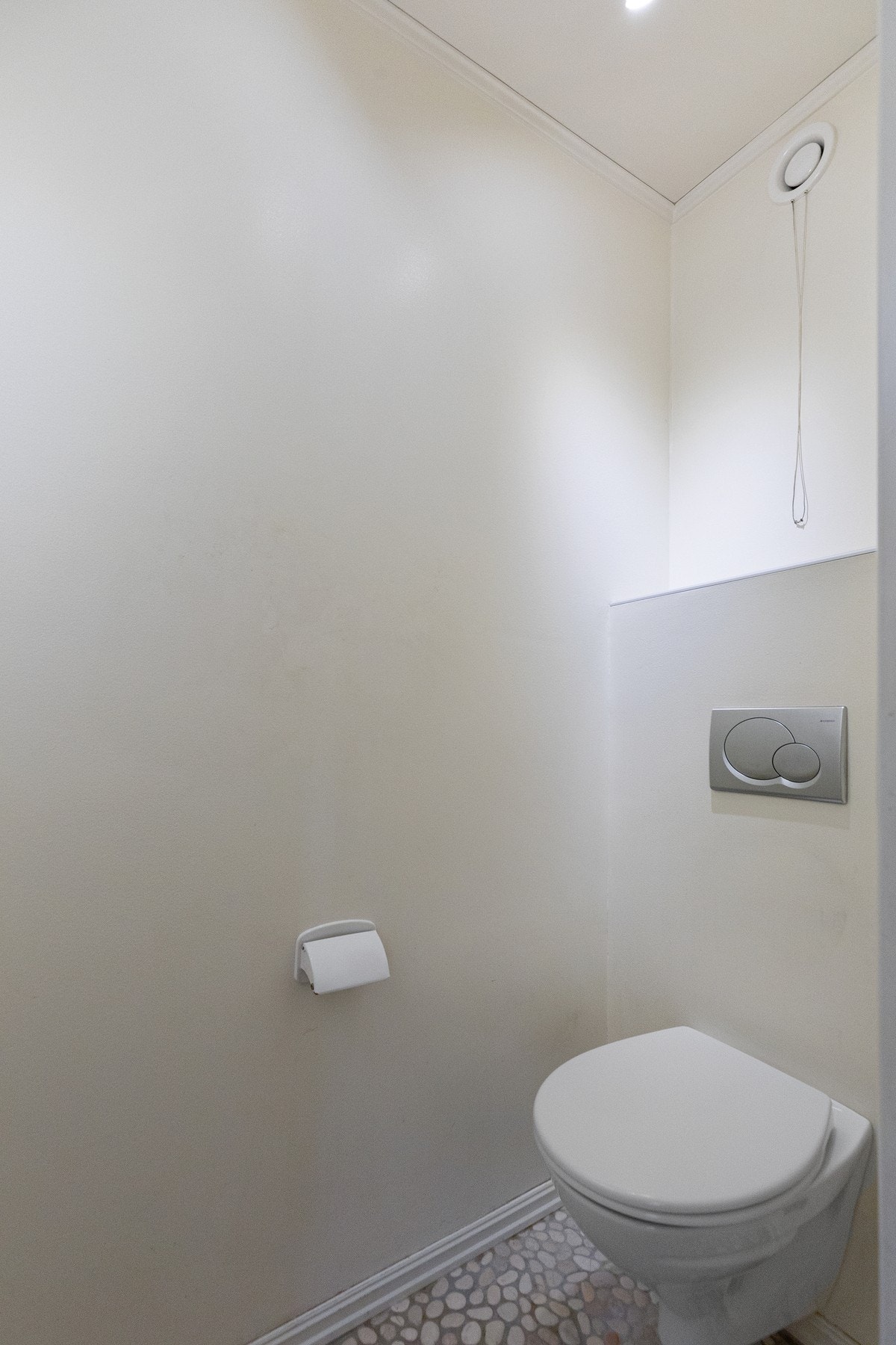 Separat toalettrom med flislagt gulv og vegghengt toalett. Galleribilde