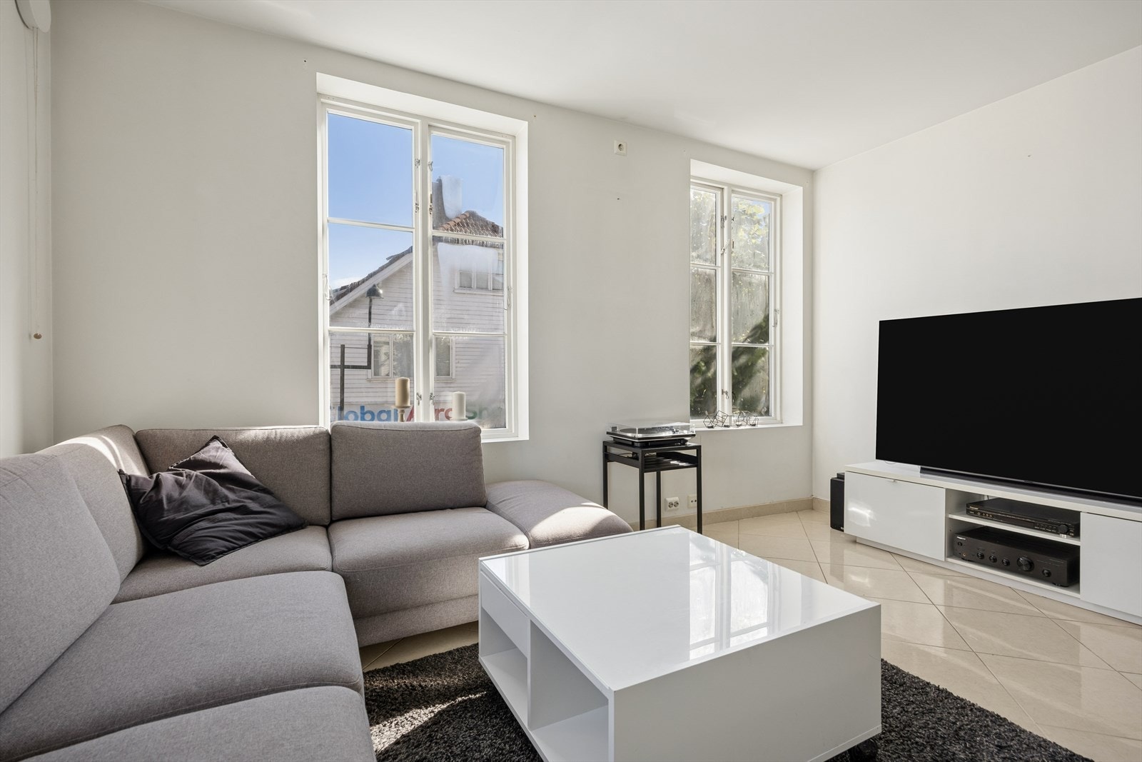 Stuen har flislagt gulv med plass til sofagruppe i tillegg til TV-vegg. Galleribilde
