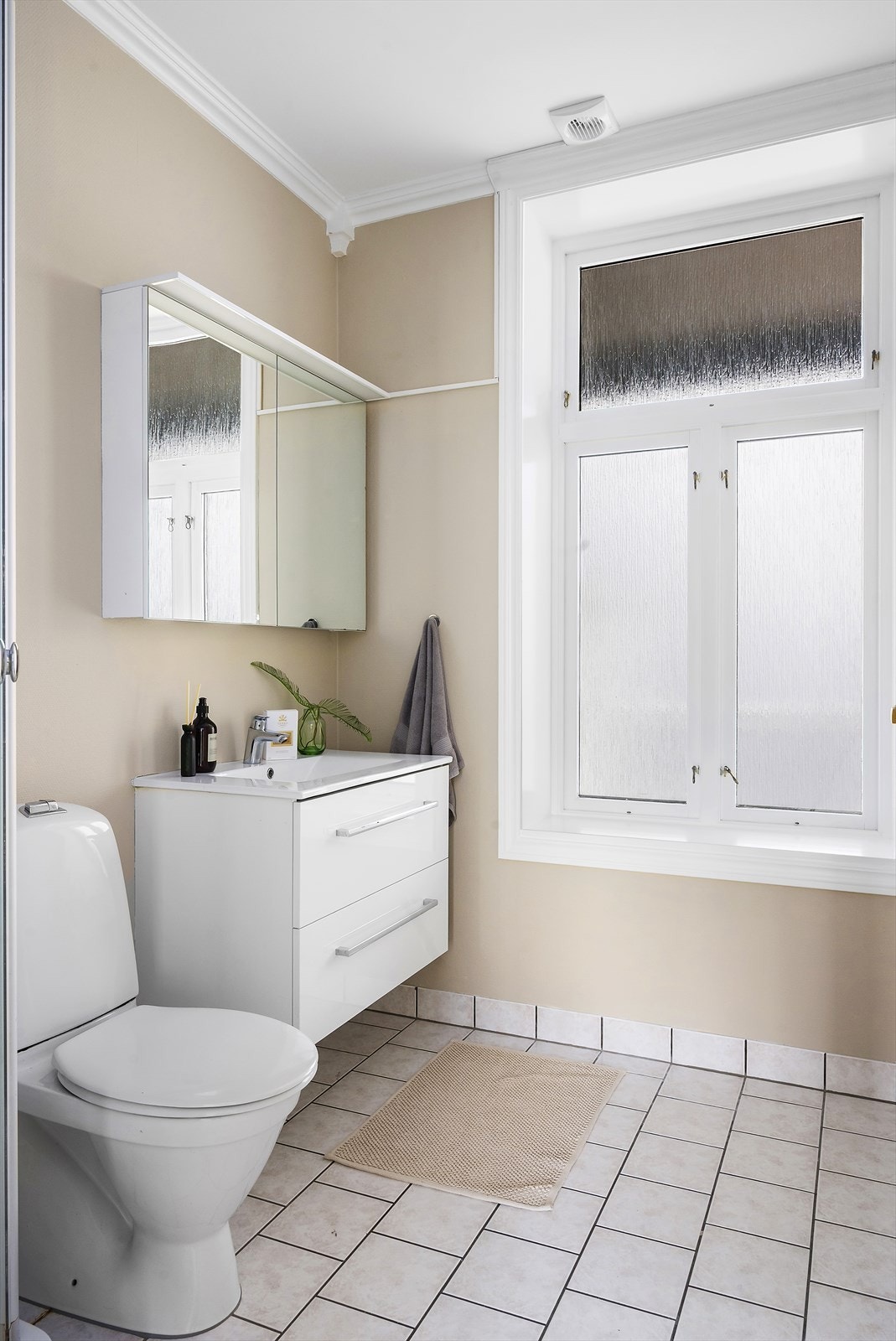 Badet inneholder toalett, dusjkabinett, vegghengt baderomsmøbel med servant, speilskap med belysning og opplegg for vaskemaskin. Galleribilde