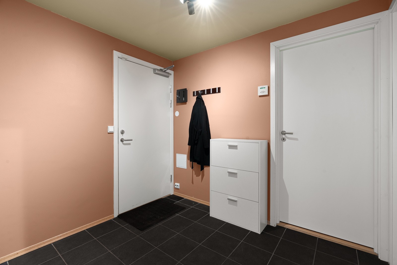 Velkommen inn! Her ønskes du velkommen inn til en fresh, flislagt entré med gulvvarme og god plass til å henge fra seg yttertøyet.