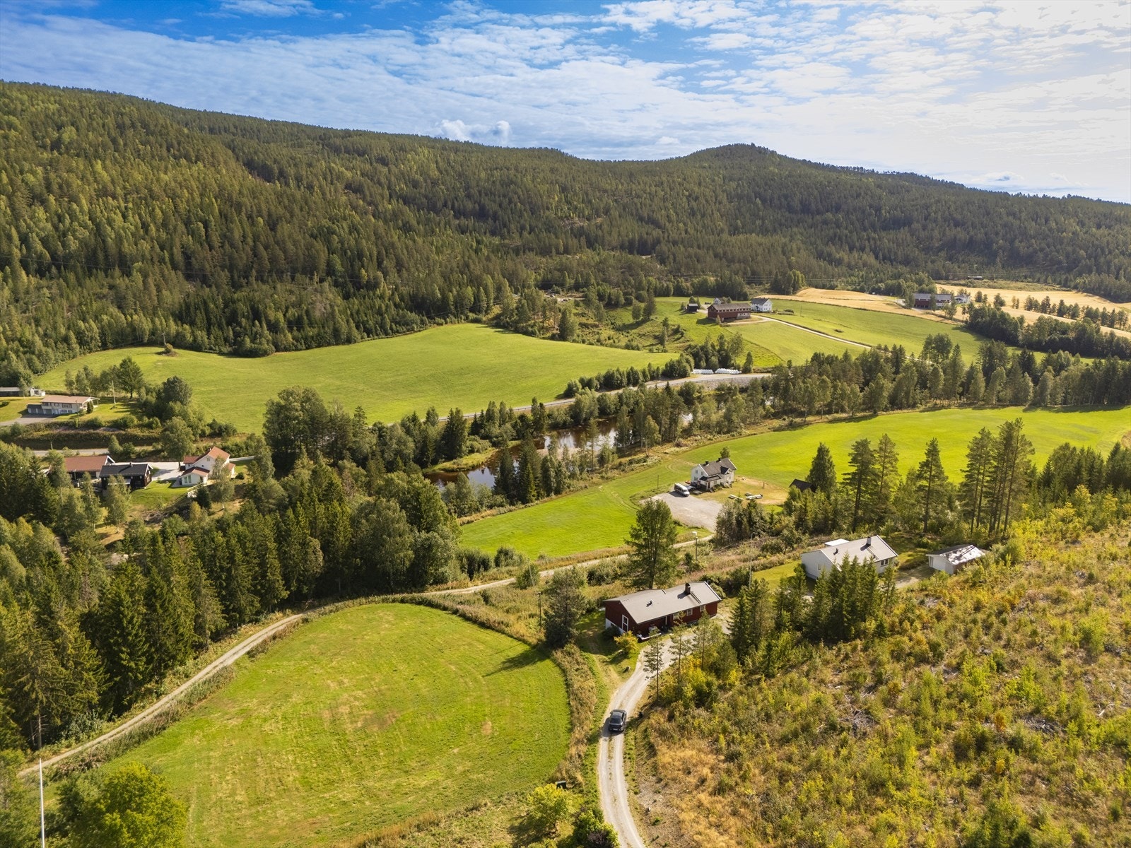 Omgitt av skog og jorder, med spredt bebyggelse. Galleribilde