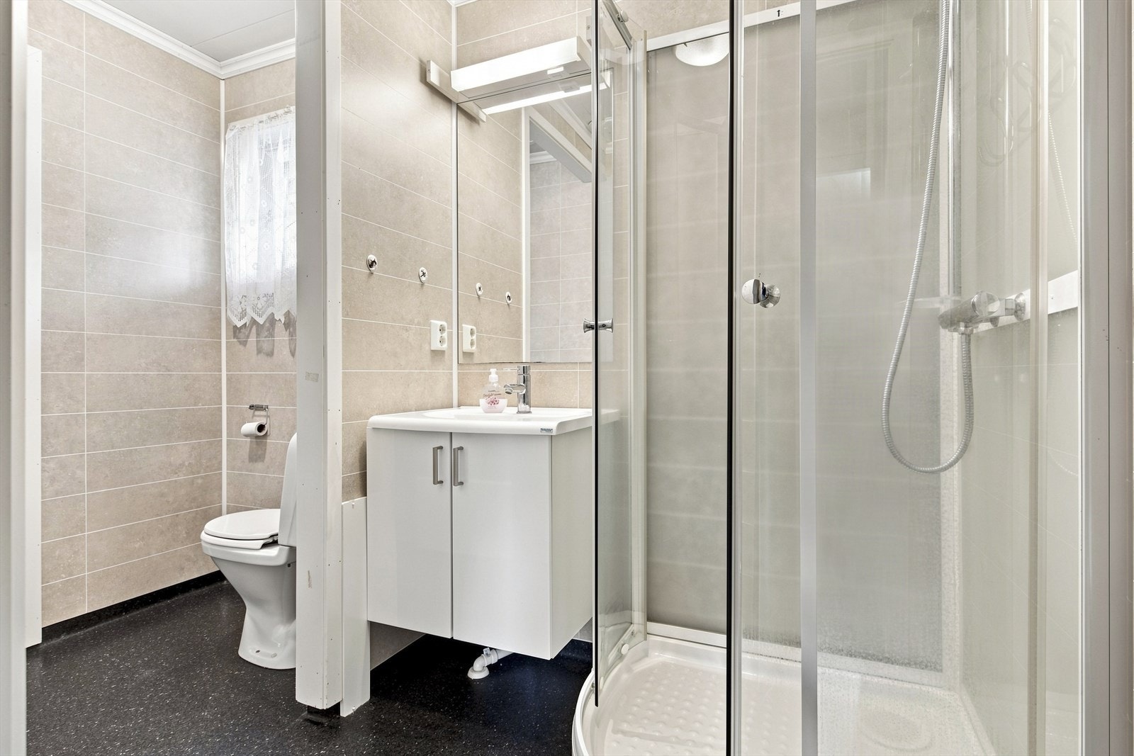 Badet er innredet med dusjkabinett, servant og toalett. Galleribilde