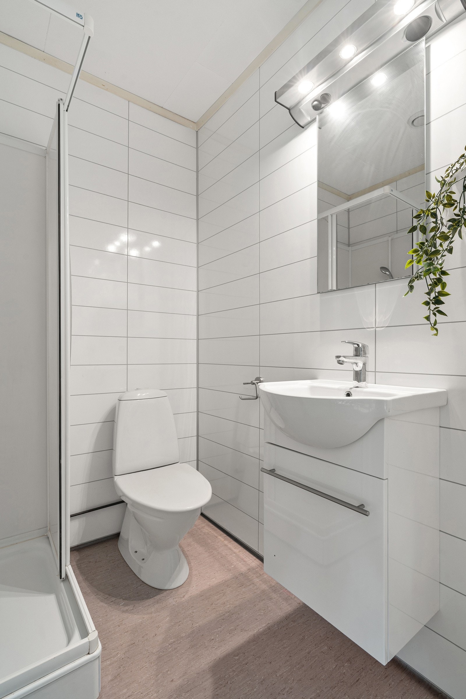 Badet er utstyrt med dusjkabinett, wc, baderomsinnredning med oppbevaring, samt opplegg for vaskemaskin.