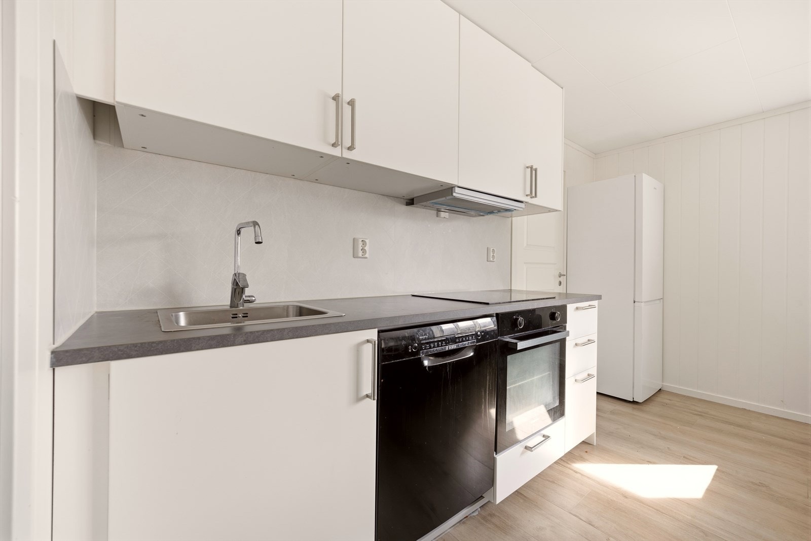 Kjøkkenet er fra perioden 2023-2025 og levert av IKEA. Innredningen har hvite, glatte fronter og laminert benkeplate med nedfelt utslagsvask. Galleribilde