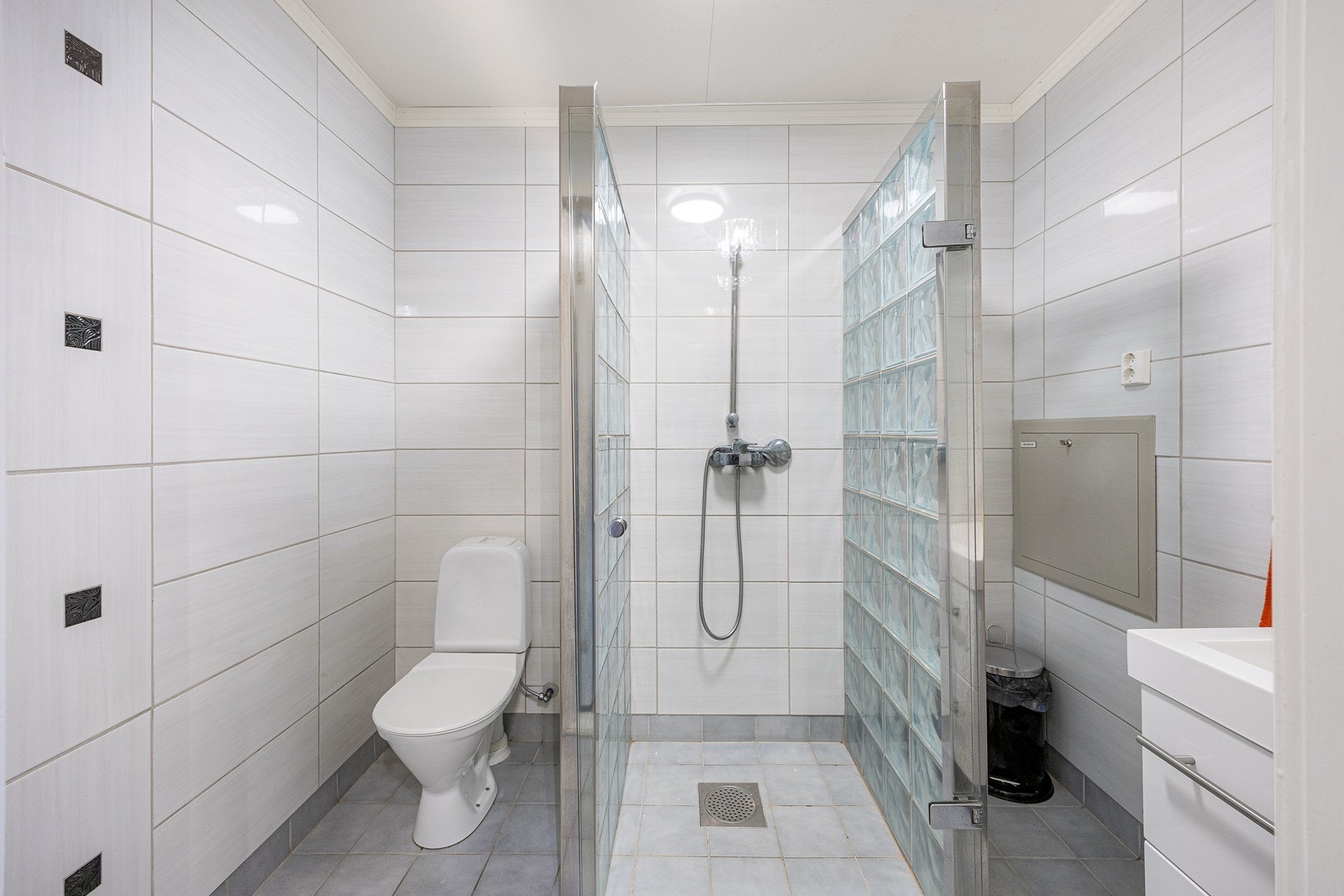 Badet i første etasje er helfliset og har lun varme i gulvet. I tillegg til toalett har badet en dusjsone som rammes inn med vegger av glassbyggerstein. Galleribilde