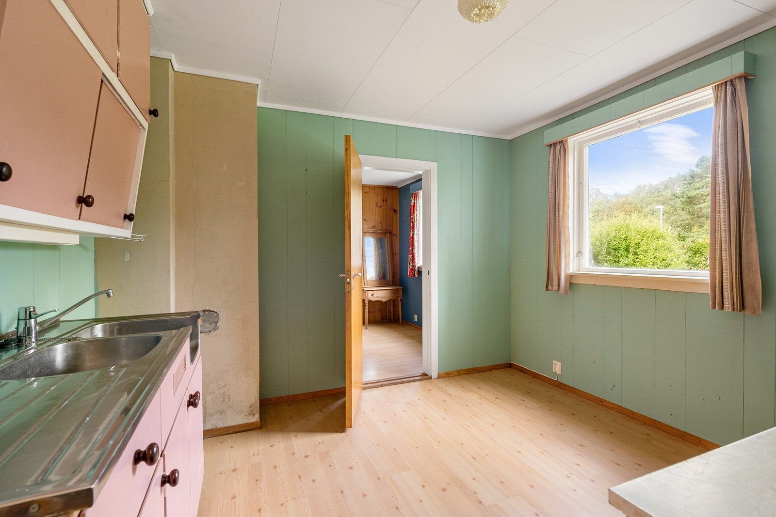 Kjøkkenet i underetasjen har en eldre innredning med glatte, malte fronter og laminat benkeplate. Galleribilde