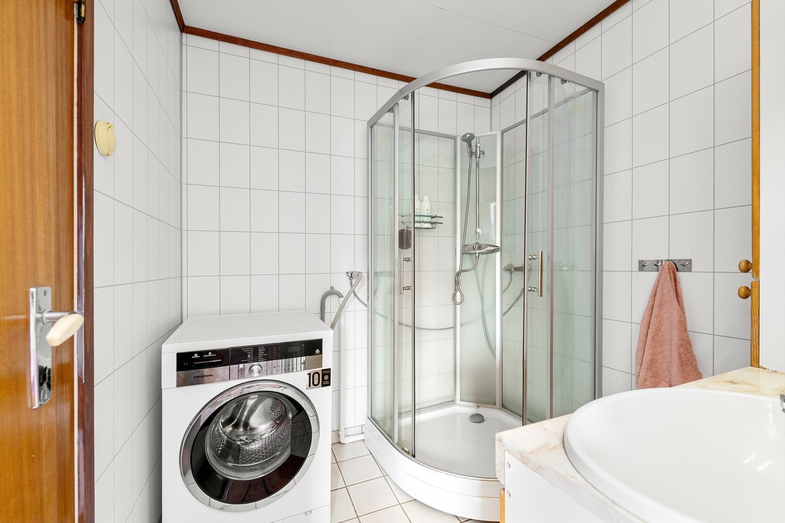 Badet er utstyrt med dusjkabinett, servantinnredning og opplegg for vaskemaskin. Galleribilde