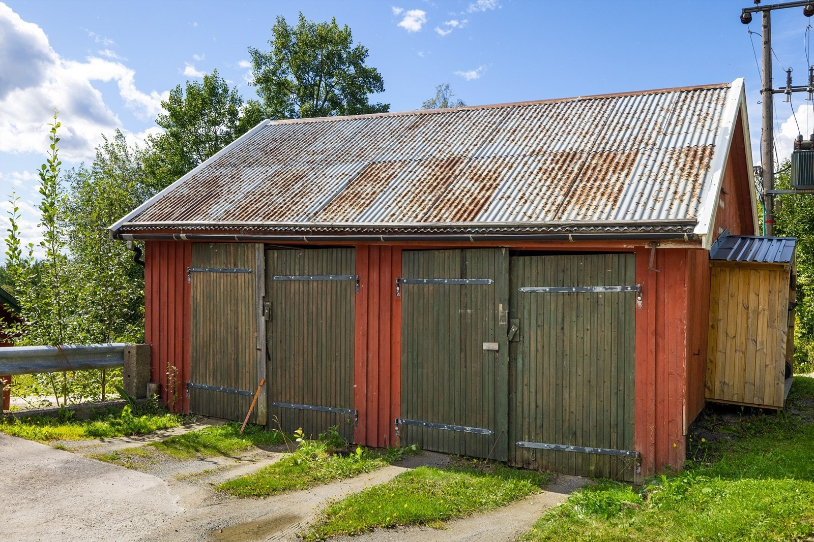 Gammelt vedskjul som er gjort om til garasje. Bygningen er i dårlig stand. Galleribilde