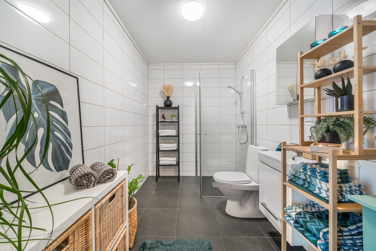 Lyst og moderne bad med delikate flislagte overflater og dusjhjørne med glassvegger. Innredningen gir gode oppbevaringsmuligheter og bidrar til et ryddig og funksjonelt rom. Det er opplegg til vaskemaskin her også. Galleribilde