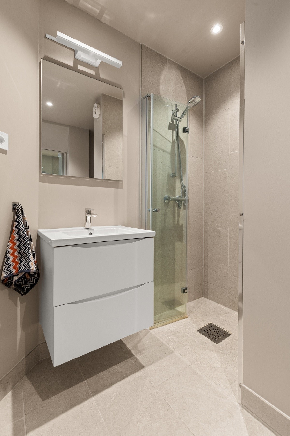 Badet ble rehabilitert i 2024 og fremstår som moderne og innbydende med elektriske varmekabler i gulv. Badet er innredet med dusjhjørne med innfellbare glassvegger, servantinnredning med gode oppbevaringsmuligheter og heldekkende servant, samt speil med i Galleribilde