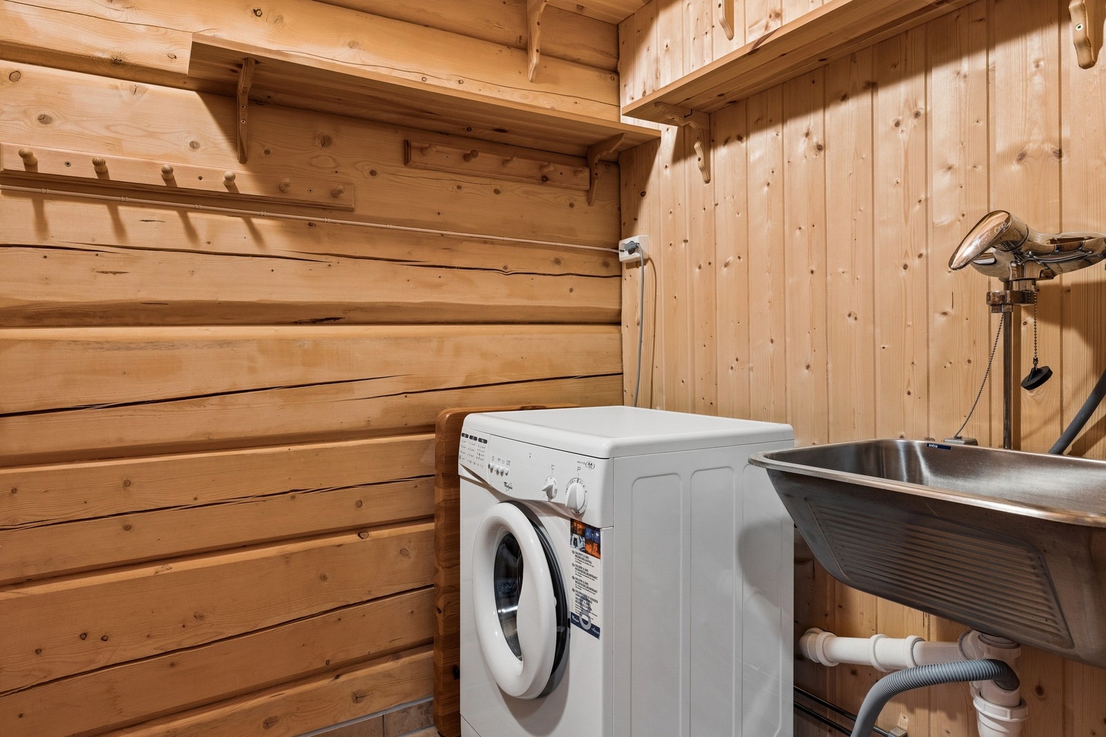 Praktisk vaskerom med gulvvarme. Vegghengt utslagsvask og blandebatteri med opplegg for vaskemaskin. Sikringsskap på vegg. Galleribilde