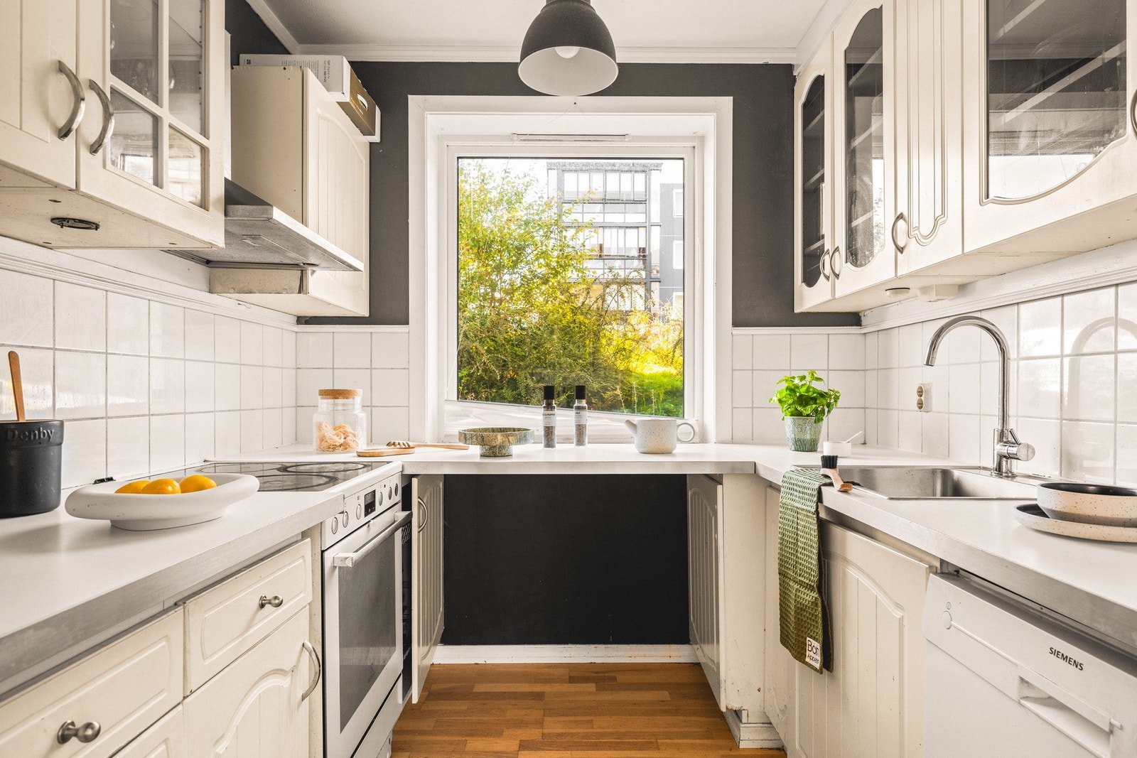 Kjøkkeninnredningen består av profilerte fronter, to av overskapene har glassfront, laminat benkeplate, over benkeplaten er det benyttet fliser, stål oppvaskkum og ventilator (kullfilter). Galleribilde