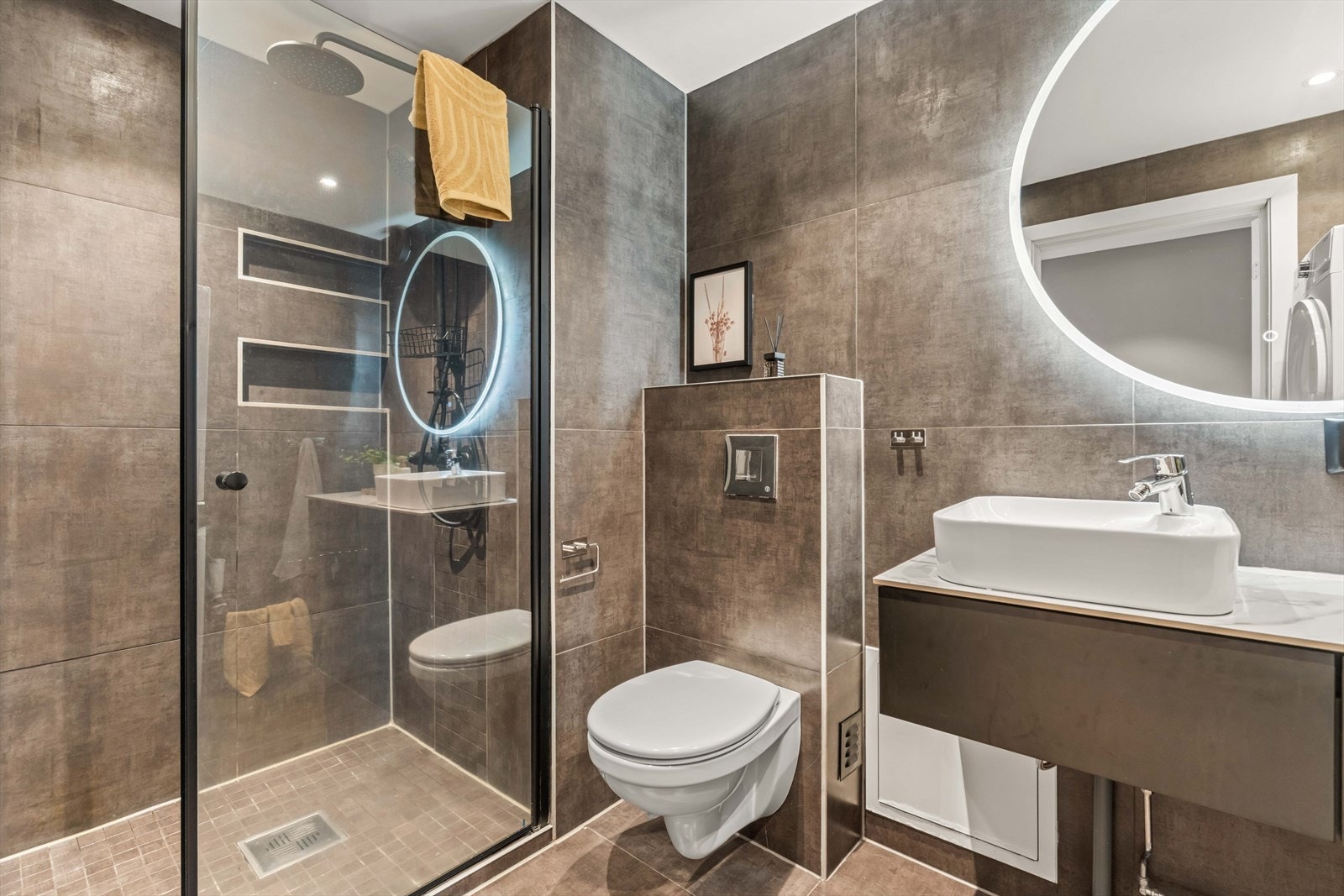 Det flislagte badet har en funksjonell utforming og sanitærutstyr med blant annet servant og toalett. Galleribilde