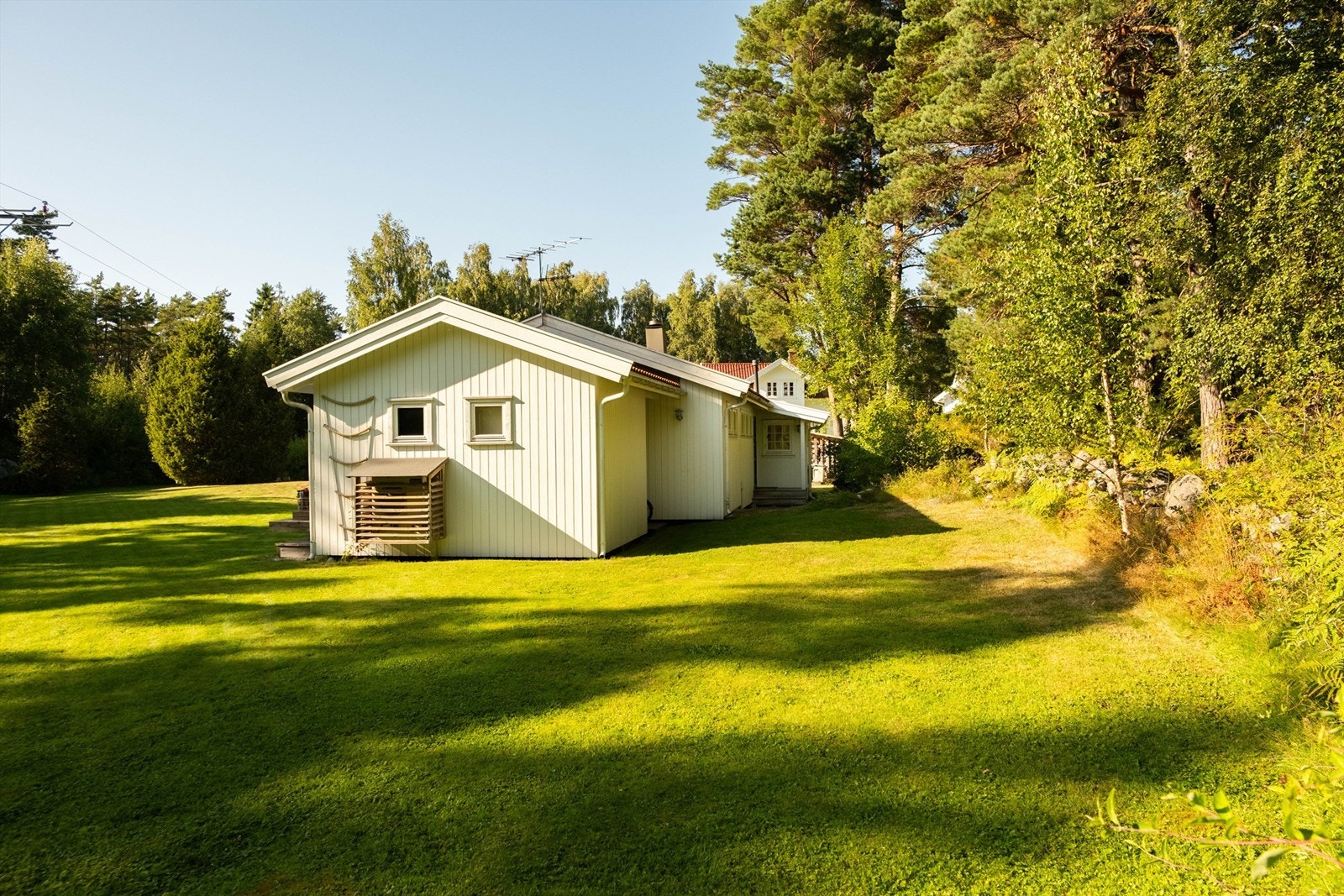 Steingjerde og naturlig vegetasjon avgrenser hagen mot Gjøkvikveien som følger østre tomtegrense. Galleribilde
